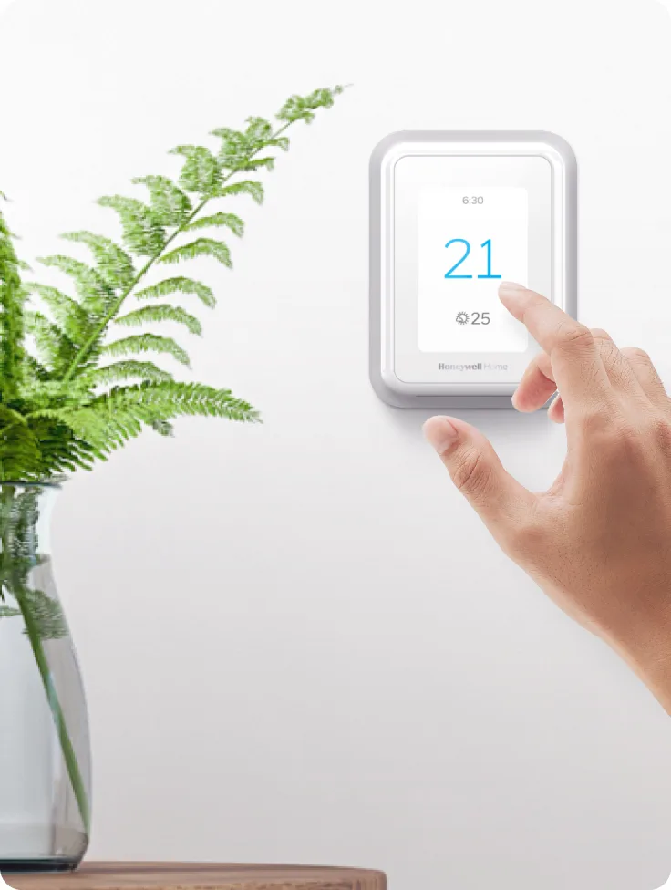 A hand adjusts a smart thermostat.