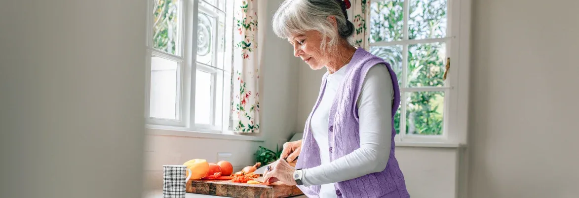 Senior woman cutting vegetables.