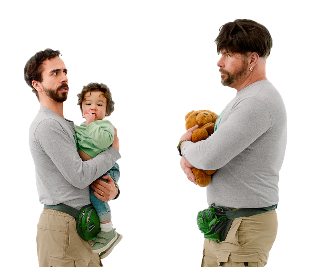 In the image, two dads with identical clothes are seen in the image, one is holding a child and one is holding a stuffed toy.