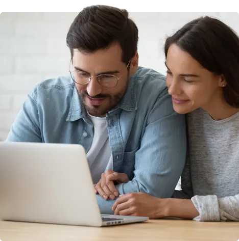 A relaxed couple sit together in front of a laptop. 