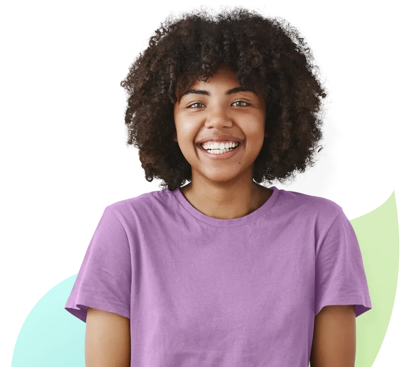 A young girl in a purple t-shirt looking straight ahead and smiling.