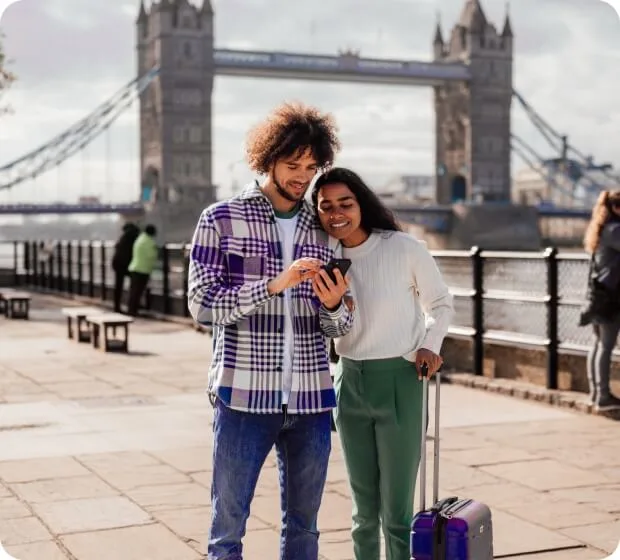 Couple using smartphone while traveling with luggage