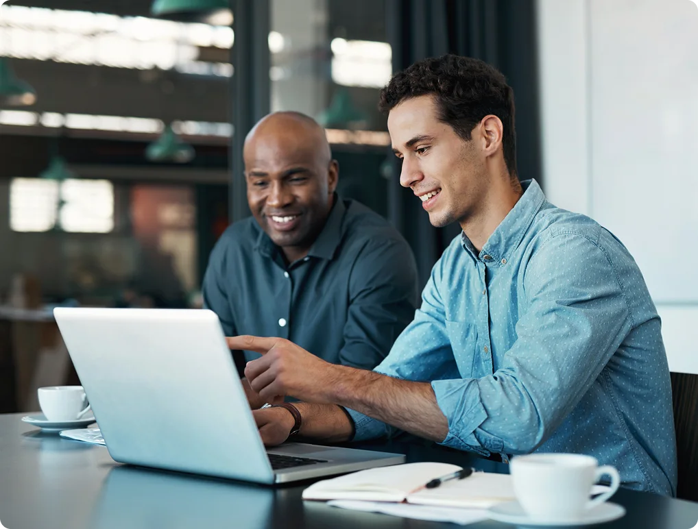 Two business professionals collaborating on a laptop in a modern office meeting.