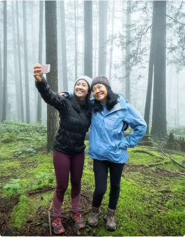 Two women taking a selfie while standing in a forest