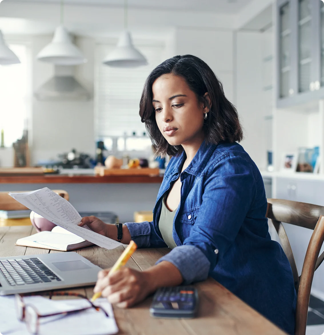 Woman reviewing documents and taking notes while working from home,