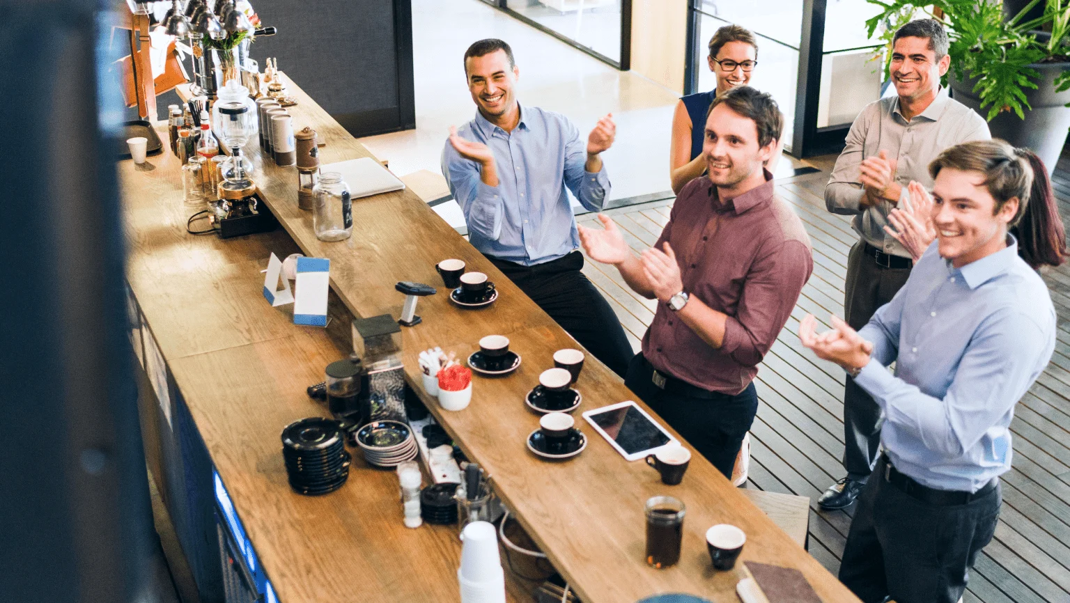 A group of coworkers having a celebratory coffee while they look at a screen