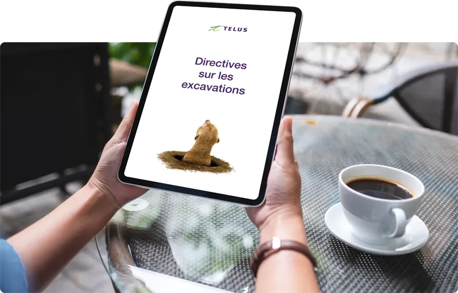 Quelqu’un tient une tablette affichant les «Directives sur les excavations» avec une photo de suricate et le logo de TELUS.