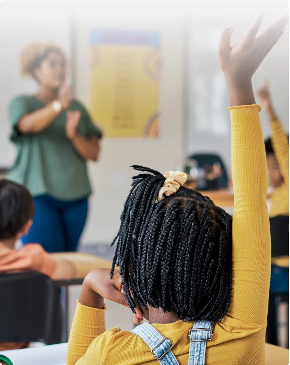 A TELUS Wise educator facing a classroom full of children raising their hands