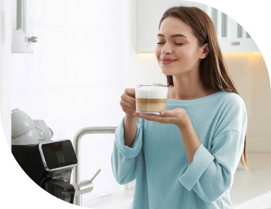 A woman enjoys her morning coffee that was ready when she woke up because her smart plug started the coffee maker.