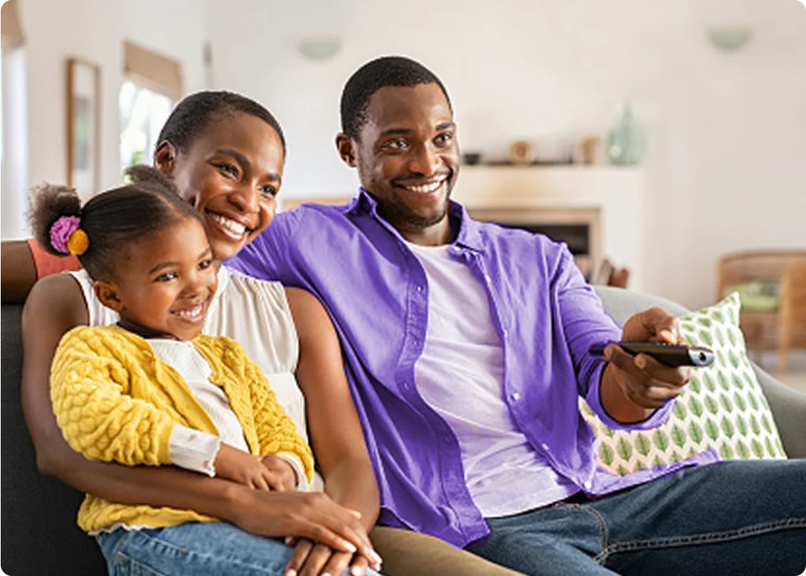 Family sitting on a couch, one person holding a remote control.