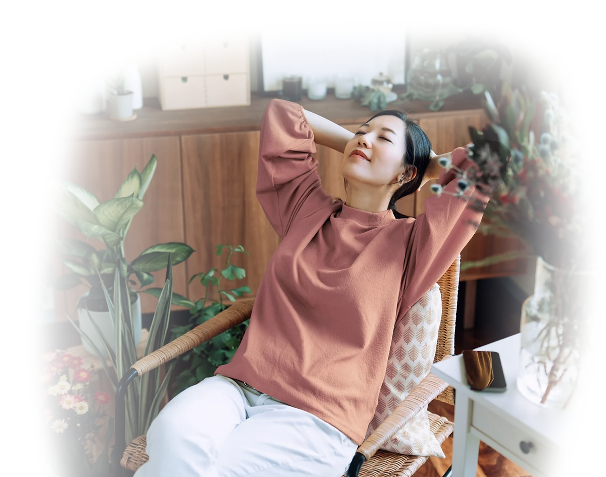 Une femme assise à un bureau qui regarde  un ordinateur portable en souriant