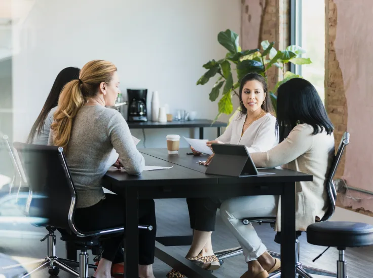 Four colleagues sitting in an office together using a digital tablet.