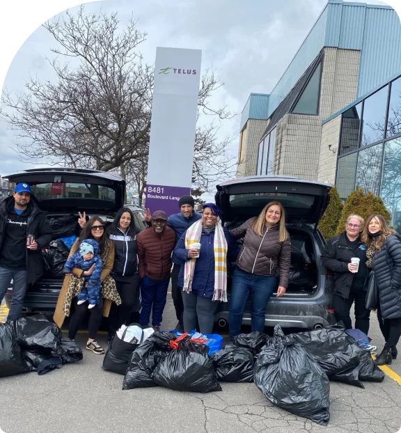 TELUS team members leading a clothing drive with several bags of donations. 