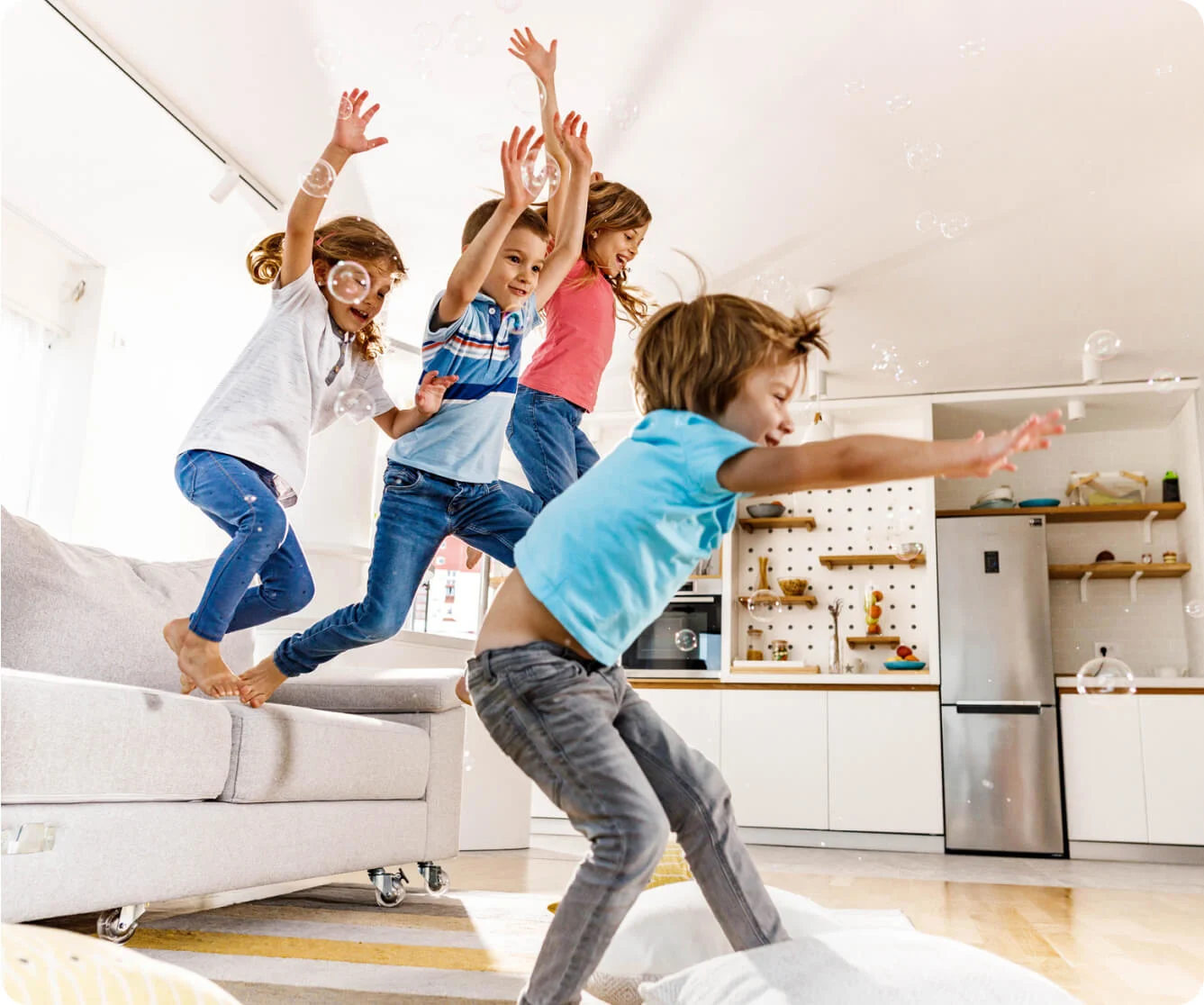 Children jumping on couch in bright living room