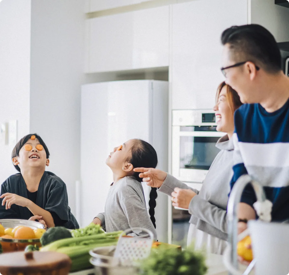 A family is seen cooking together and laughing in the kitchen. 