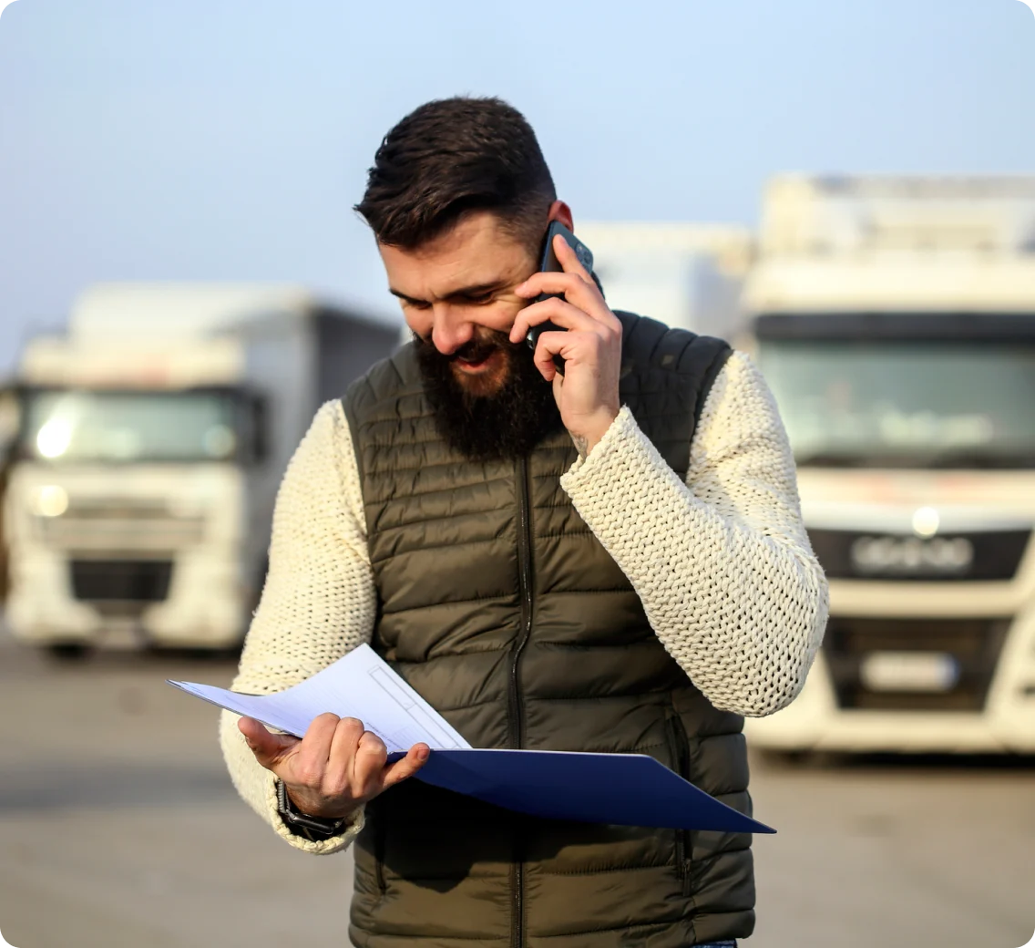 A driver in front of trucks talking on the phone.