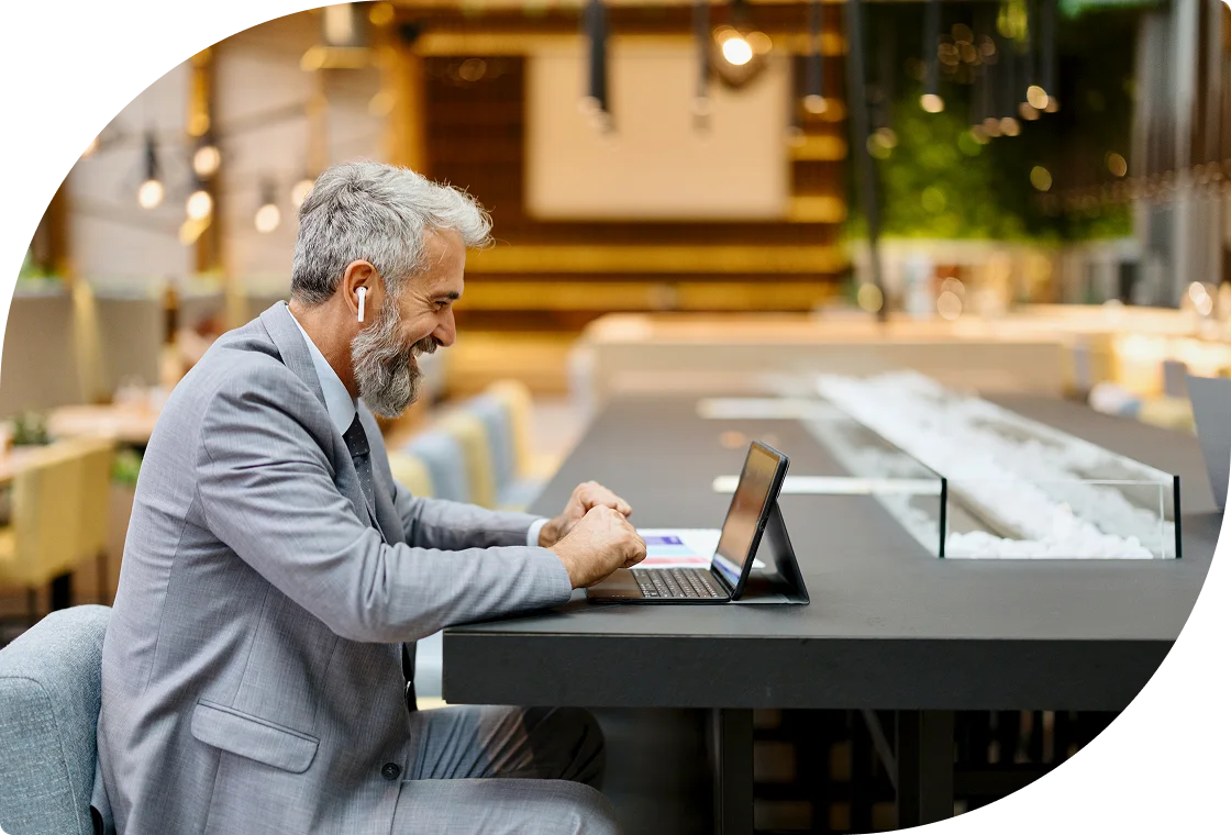 Business professional working on laptop with wireless earbuds in contemporary workspace.