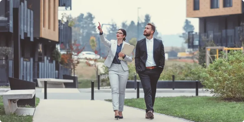 Man walking with real estate agent on a sidewalk looking at nearby buildings