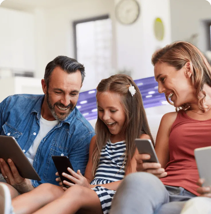 A family looking at their smartphones and tablets, all connected to TELUS PureFibre Internet.
