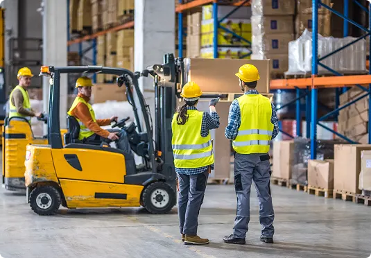 Warehouse workers managing forklift operations in the distribution center.