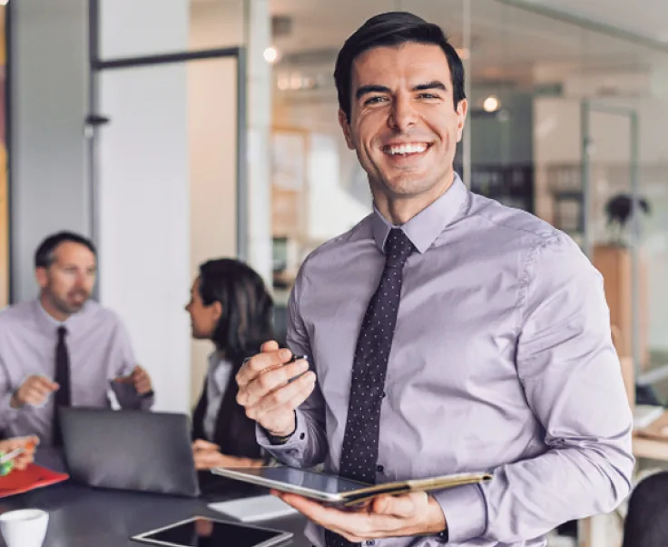 Smiling professional holding a tablet in a modern office