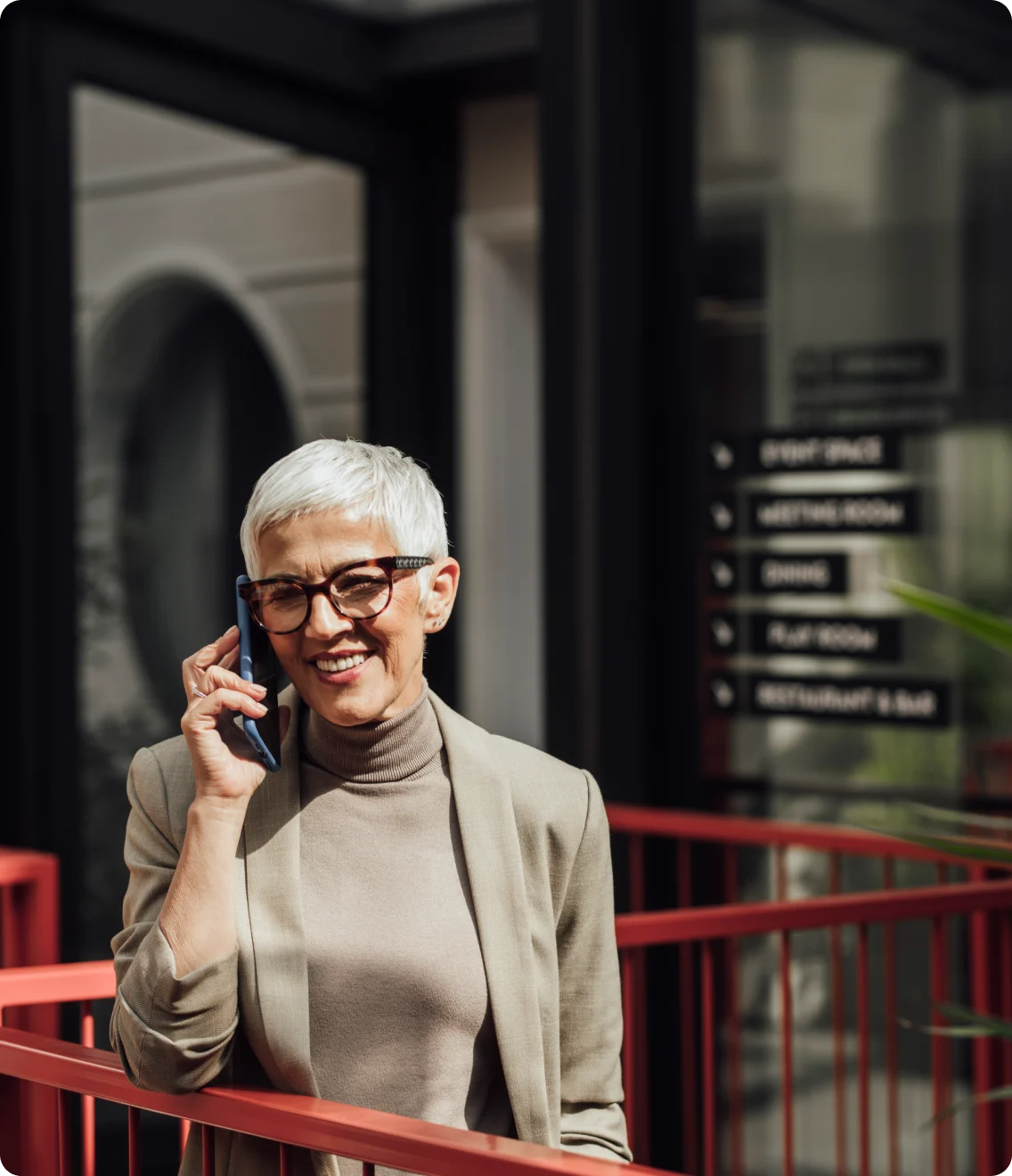 A professional takes a call outside an office building.
