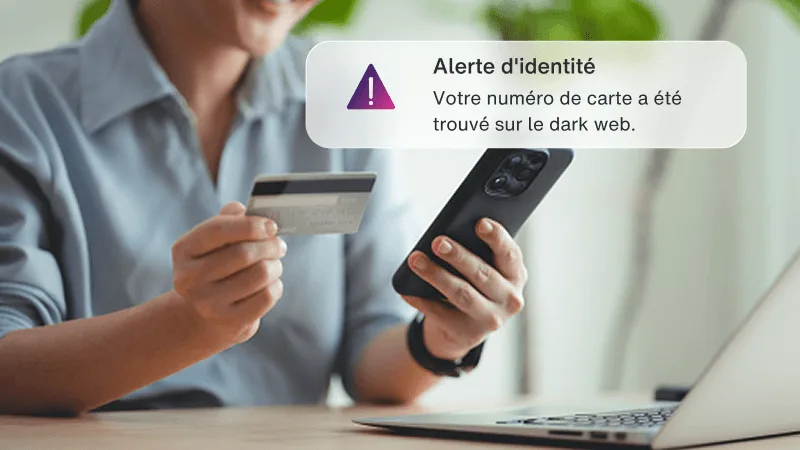 Une femme tenant une carte de crédit et un téléphone près d'un ordinateur portatif, avec une fenêtre qui dit qu’il s’agit d’un site frauduleux.