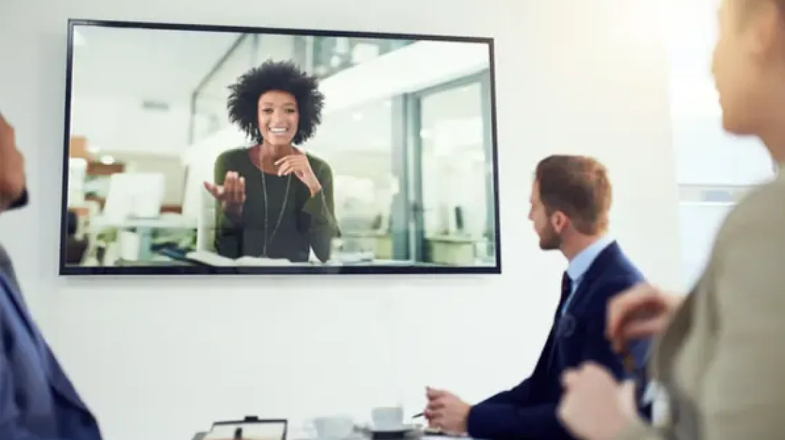 Woman on TV video chatting with people in a business conference call