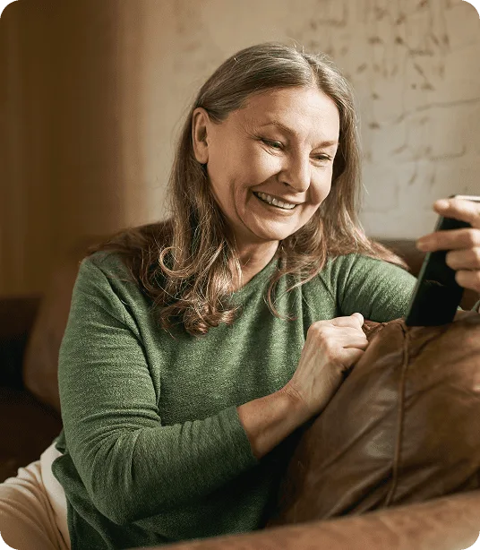 Une femme âgée souriant en utilisant l'application mobile Mes Soins TELUS Santé sur son téléphone intelligent.
