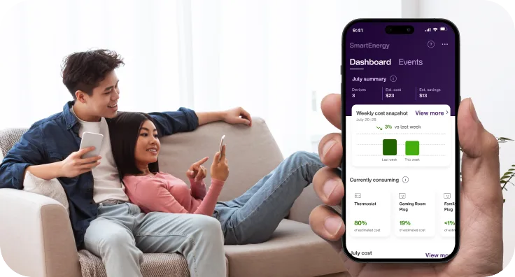 A couple relaxes on a couch using their smartphones, while a hand holds a phone displaying the SmartEnergy app dashboard, showing energy consumption and savings.