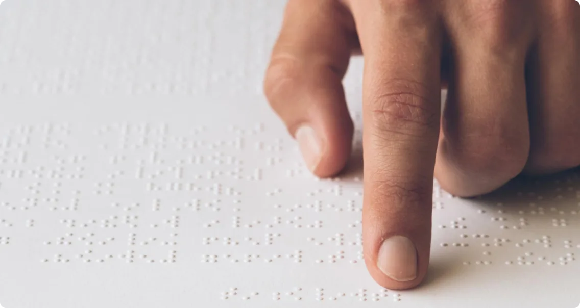 A person’s finger running over a Braille surface
