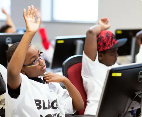 Two students raising their hands in a classroom