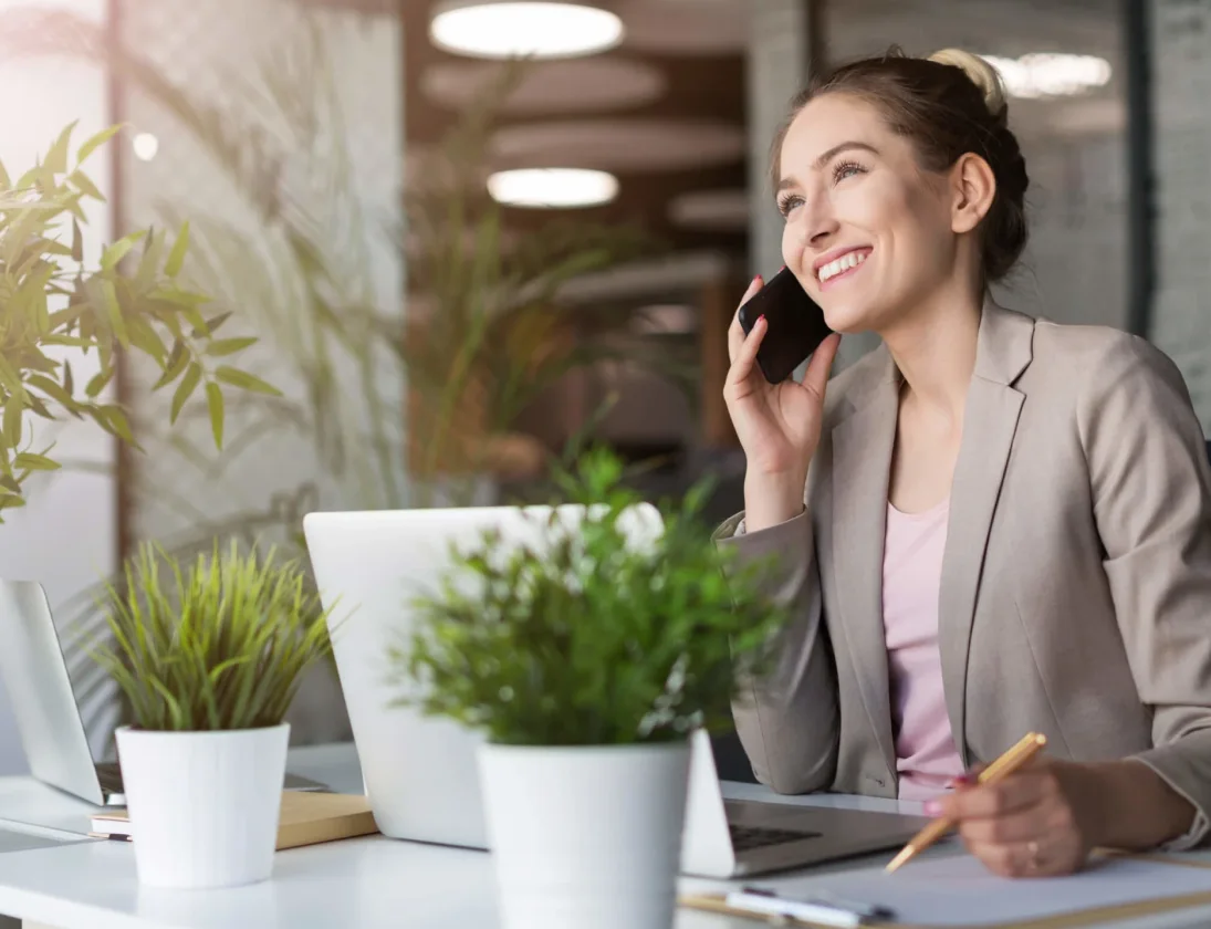 Une femme souriante au téléphone travaillant à son bureau