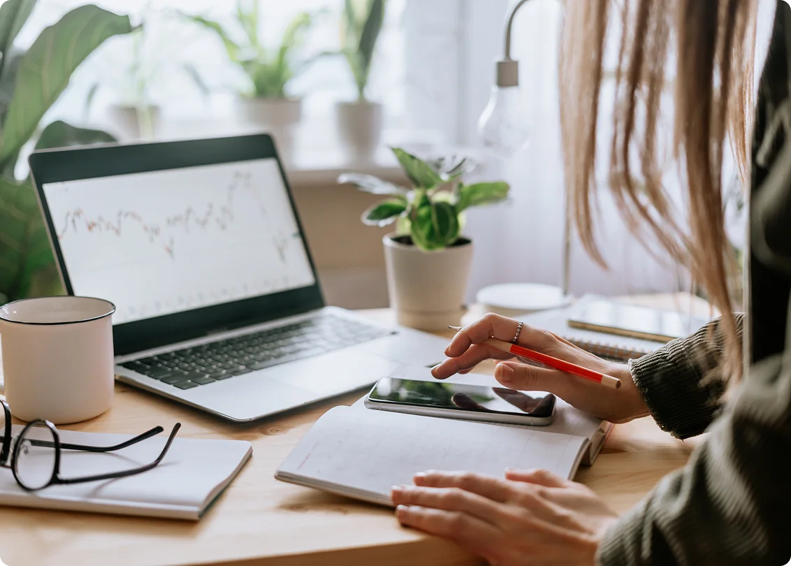 Professional working on laptop and smartphone at home office desk.