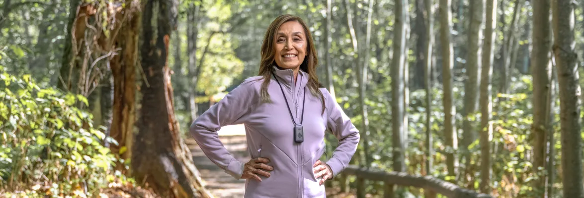 Woman in the forest with a TELUS Health medical alert pendant.