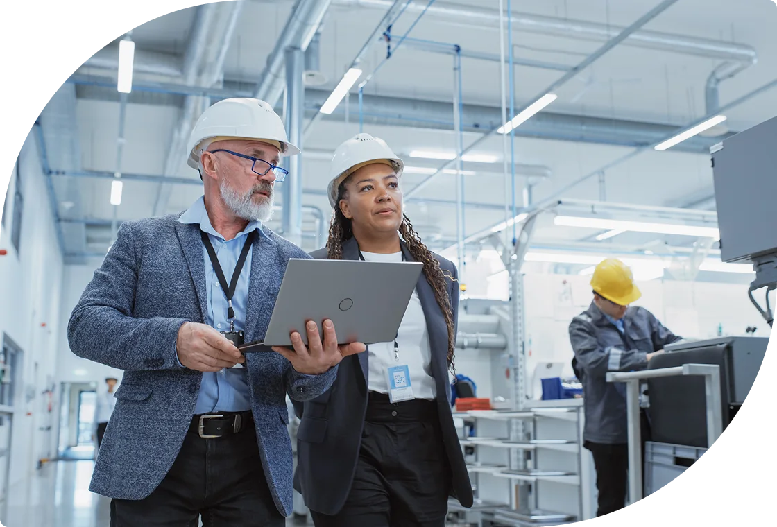 Manufacturing managers reviewing facility operations on tablet in industrial plant.