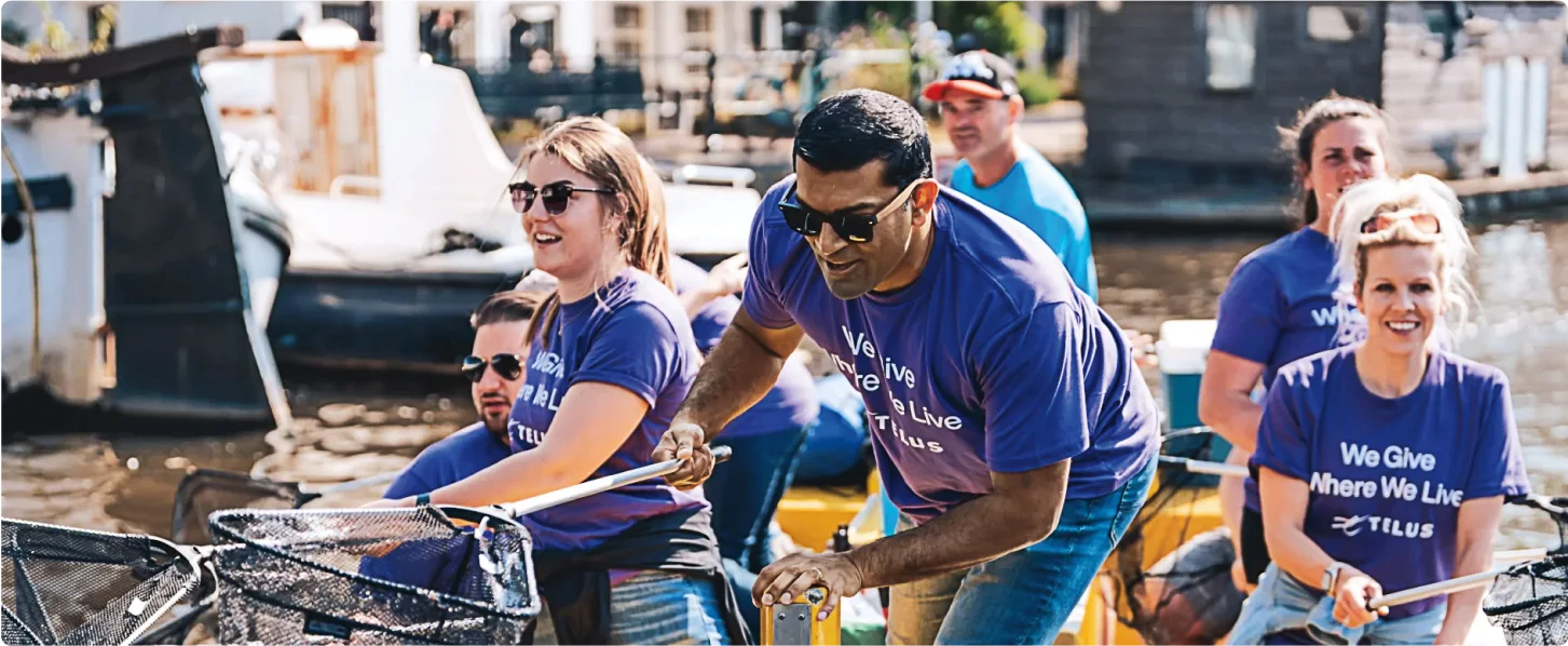 TELUS team members on a boat, collecting plastic waste from a canal in Amsterdam.