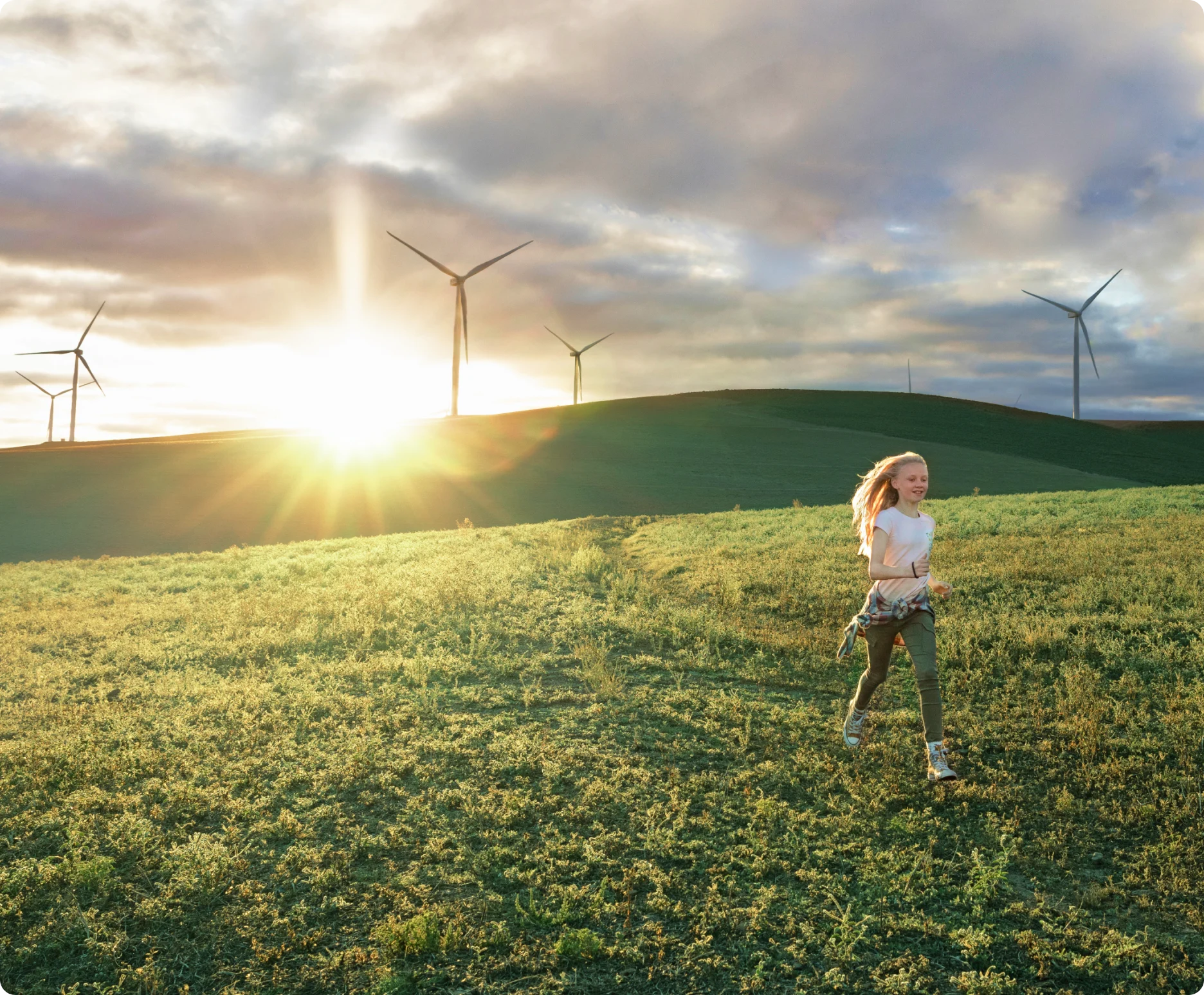 Une femme marchant dans un champ avec des éoliennes en arrière-plan.