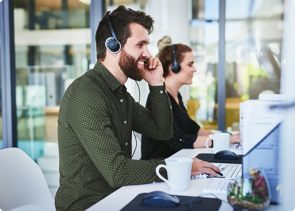 Customer service representative with headset assisting clients at workstation.