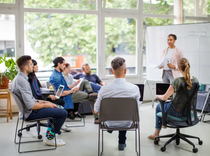 A group of people attending a workshop and facing the presenter.