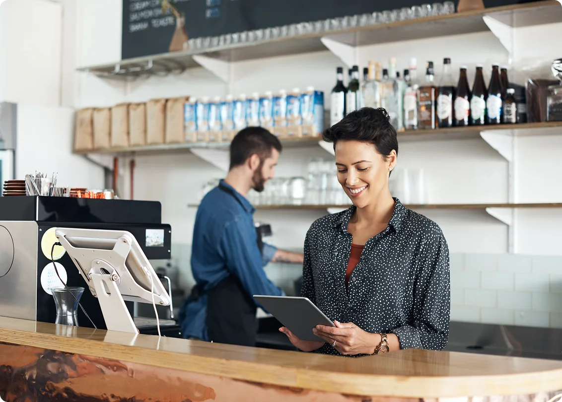 Cafe owner using tablet at point of sale counter.