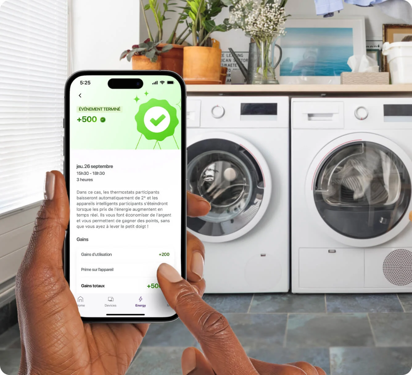 Personne faisant la lessive avec en main un appareil sur lequel le résumé d’un défi d’économie d’énergie relevé s’affiche dans l’application TELUS MC+. 