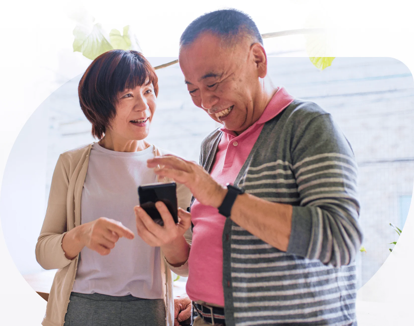 Two seniors smiling together and holding a mobile phone.