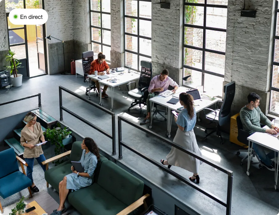 Flux en direct d'une caméra de sécurité montrant un espace de bureau moderne et ouvert, avec des employés qui travaillent à leurs postes dans un environnement collaboratif.