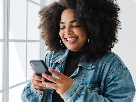Woman smiling while researching weight loss medication options on her smartphone