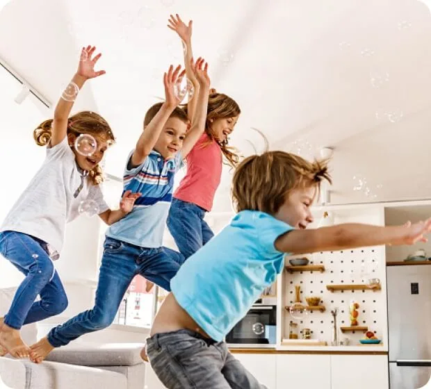 Children jumping on couch in bright living room