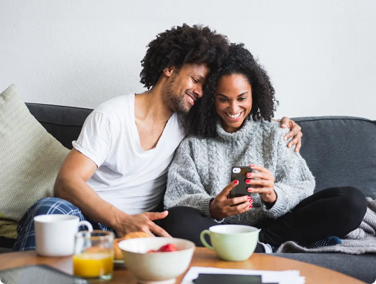 Couple assis sur un canapé et regardant les vidéos captées par les caméras sur l’application TELUS MC+.