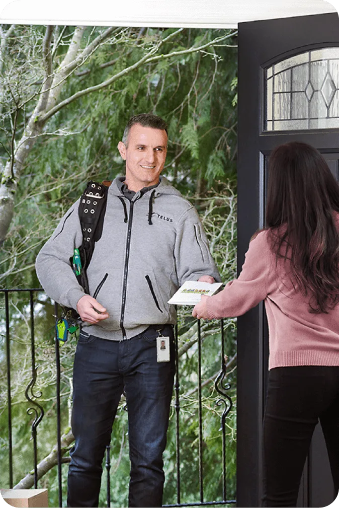 A TELUS Custom Home Security installation technician interacting with a customer at her front door.