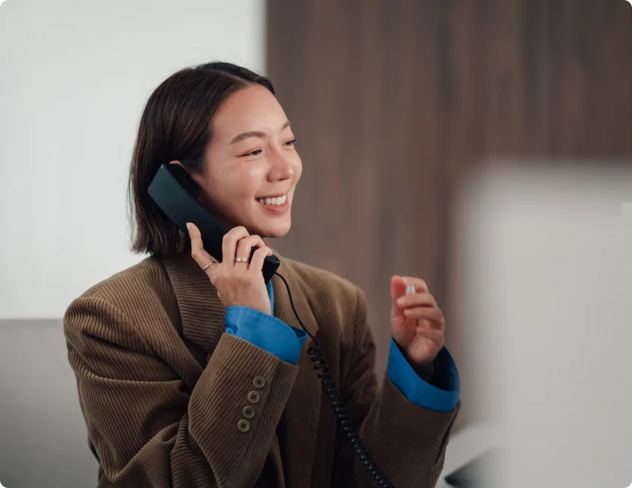 Professional smiles while speaking on a desk phone.