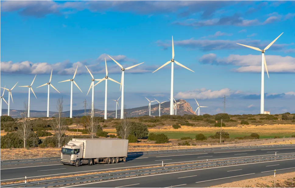 A delivery truck driving down a road and passing through a wind farm.